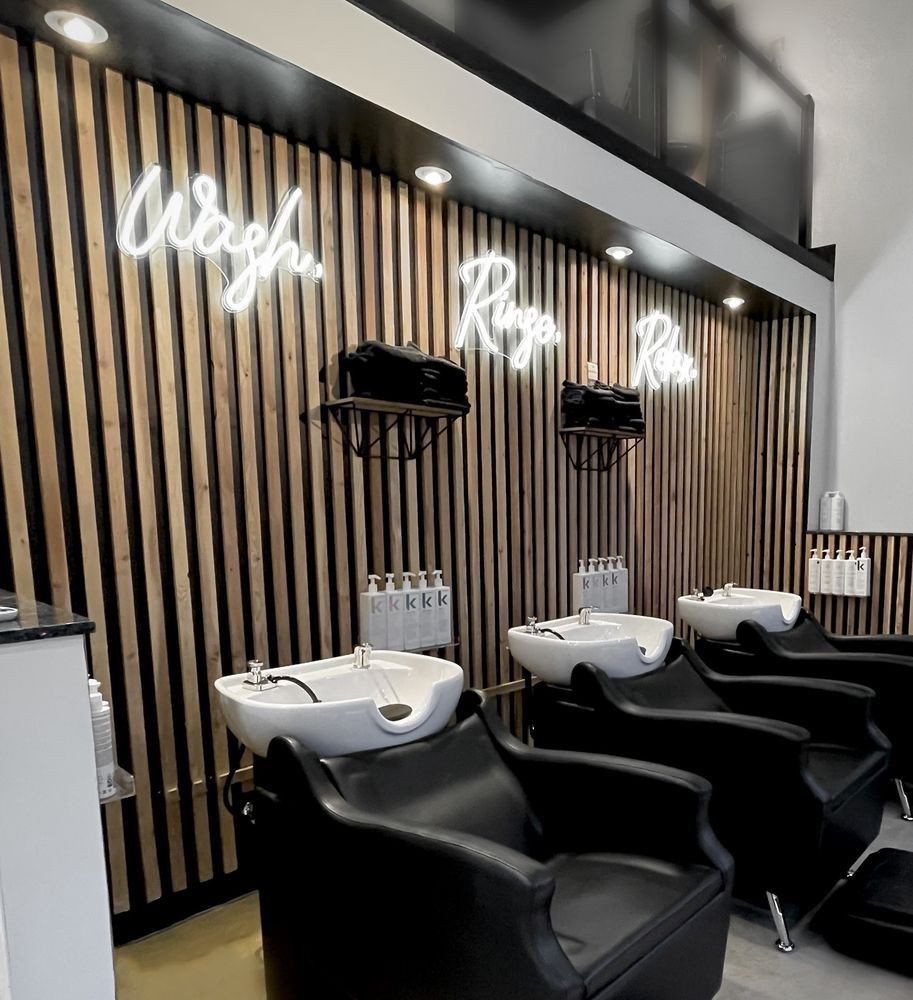 Lush Collective wash lounge with white basins, black reclining chairs and a wood slat wall